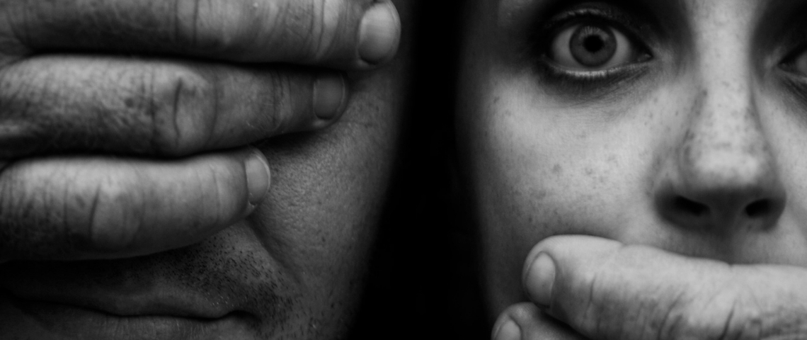 Un homme aux yeux bandés ferme la bouche d'une jeune femme