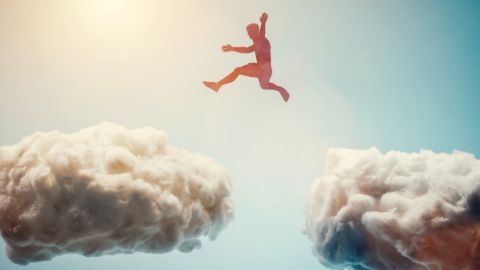 Un homme saute de nuages en nuages dans le ciel