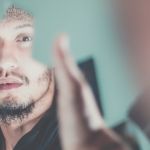 Un homme se regarde dans un miroir cassé