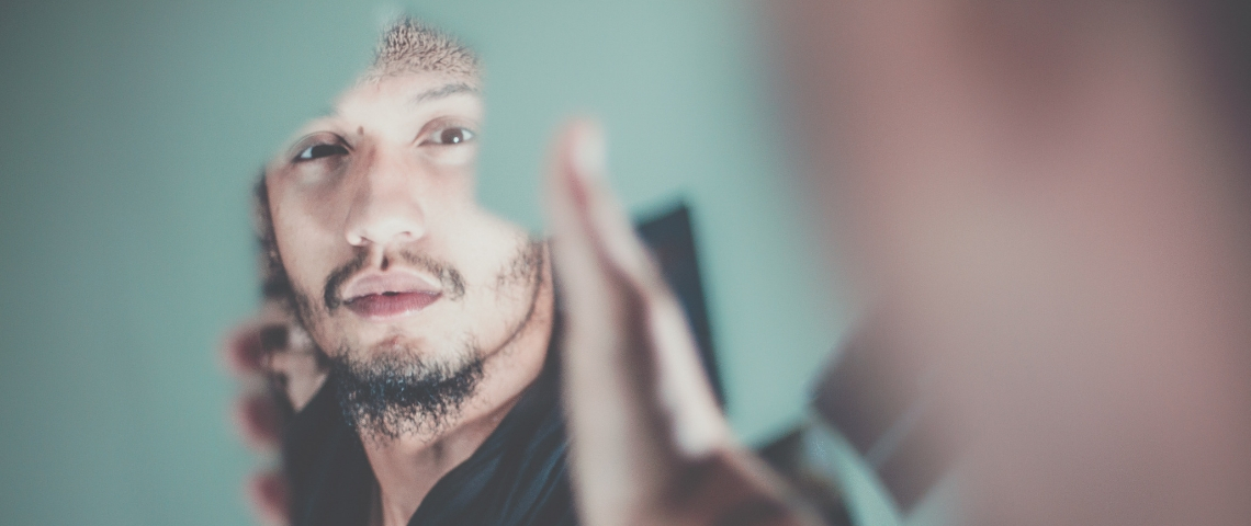 Un homme se regarde dans un miroir cassé