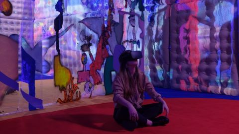 Jeune femme assise par terre dans un musée avec un casque de réalité virtuelle.