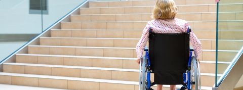 Mobilité inclusive : la France à la traîne Femme en fauteuil roulant devant des escaliers