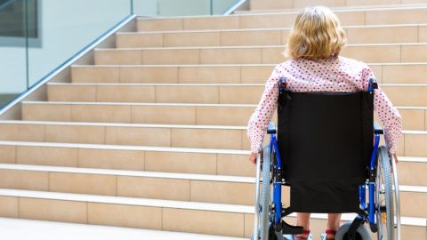 Mobilité inclusive : la France à la traîne Femme en fauteuil roulant devant des escaliers