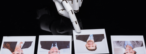 Ethique de l'intelligence artificielle Doigt robotique pointe la photo d'un homme jeune parmi quatre photos.