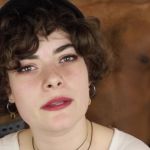 Une jeune femme qui parle devant des homme torse nus