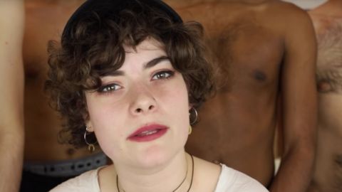 Une jeune femme qui parle devant des homme torse nus