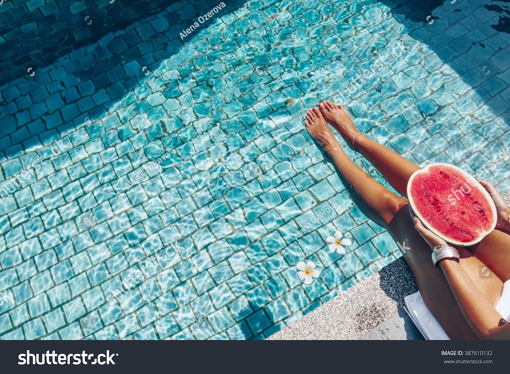 une fille tient une pastèque dans une piscine