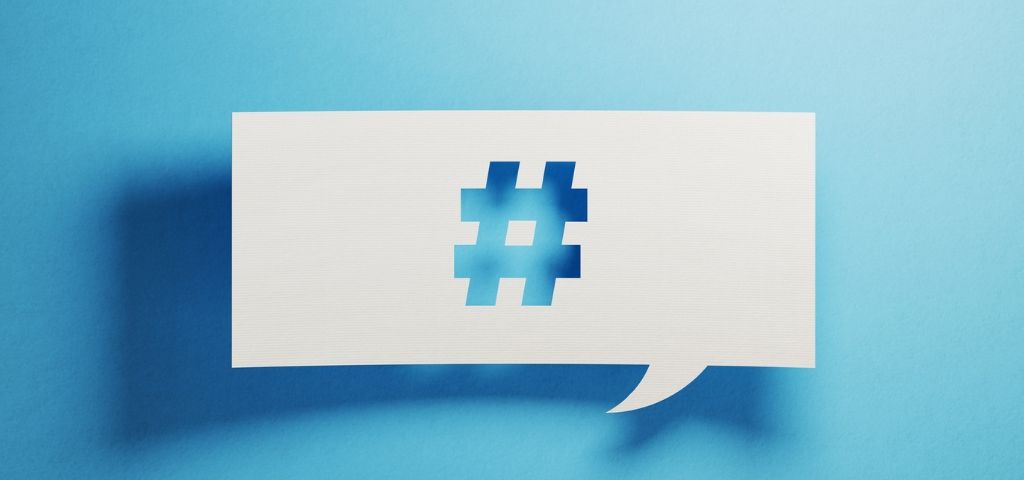 Qui sont les meilleurs dircom sur Twitter ? Un papier perforé avec un symbole de hashtag sur un fond bleu