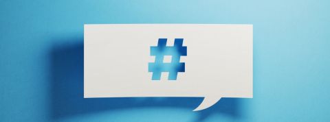 Qui sont les meilleurs dircom sur Twitter ? Un papier perforé avec un symbole de hashtag sur un fond bleu