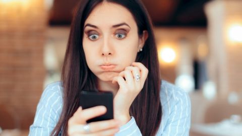 Une femme brune en train de s'énerver derrière son téléphone portable