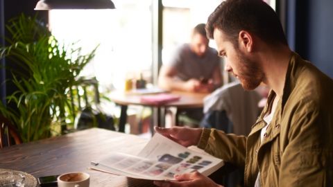 un homme lit un magazine dans un bar