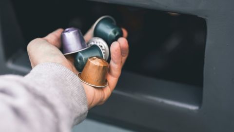 Un homme jette des capsules Nespresso dans une poubelle pour produits recyclables