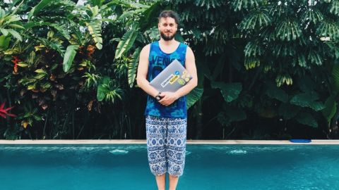 Un homme en train de tenir un ordinateur devant une piscine