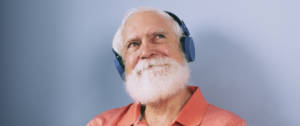Un vieil homme à barbe blanche écoute de la musique à travers un casque audio
