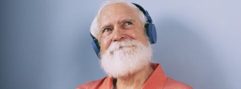 Les podcasts érotiques Un vieil homme à barbe blanche écoute de la musique à travers un casque audio