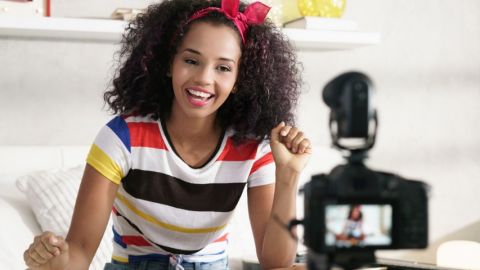 Une jeune femme métisse en train de se filmer dans sa chambre