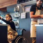 une personne en chaise roulante en train de servir un client au comptoir au restaurant