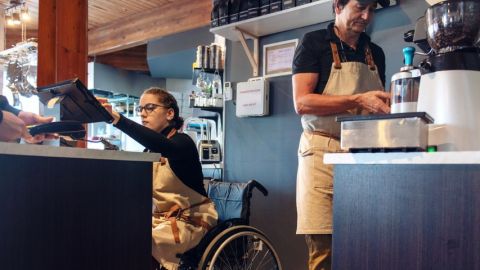 une personne en chaise roulante en train de servir un client au comptoir au restaurant