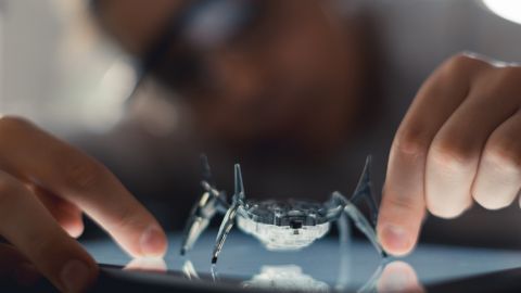 Robot araignée observé par une personne portant des lunettes.