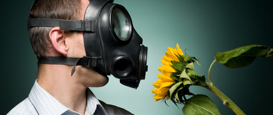 Pourquoi la RSE pose problème Un homme avec un masque à gaz en train de respirer un tournesol