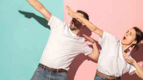 deux personnes en t-shirt blanc font des gestes de victoire sur fond bleu et rose
