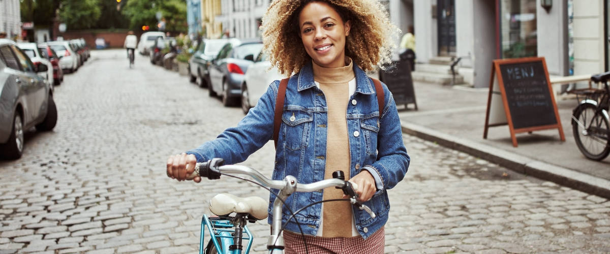 Où consommer durable et responsable à Paris ? Une femme qui marche à côté de son vélo dans une ville