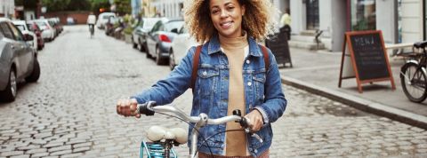 Où consommer durable et responsable à Paris ? Une femme qui marche à côté de son vélo dans une ville