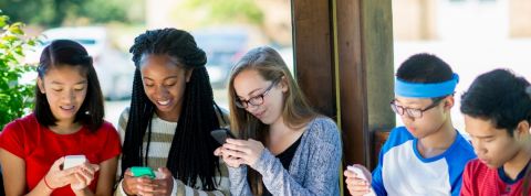 Les ados et leur portable Des collégiens en groupe qui regardent leur portable