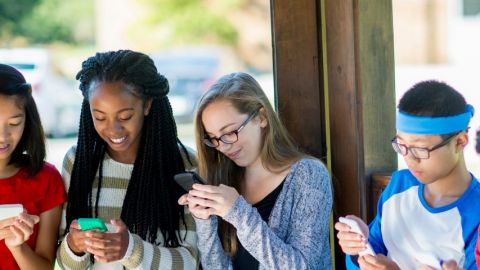Des collégiens en groupe qui regardent leur portable