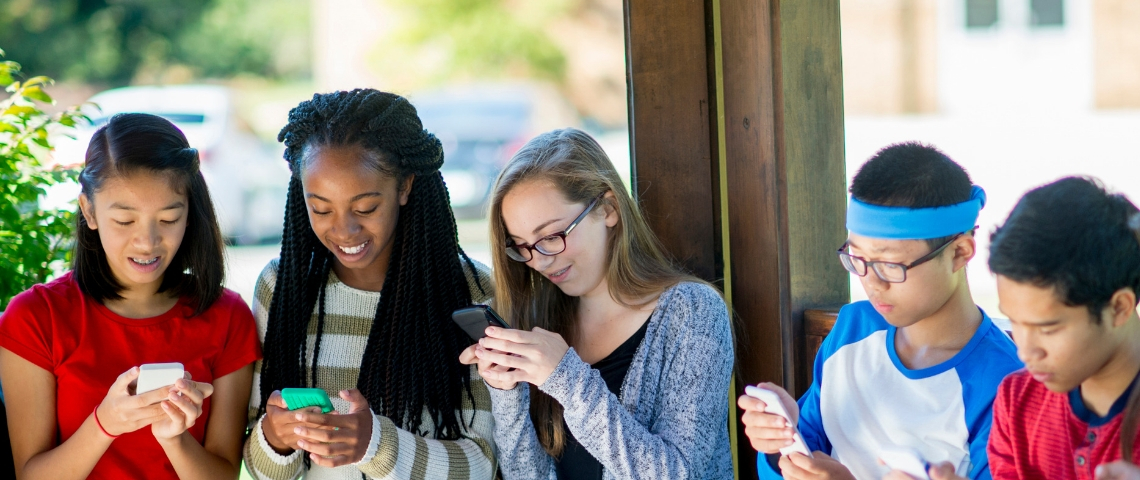 Les ados et leur portable Des collégiens en groupe qui regardent leur portable