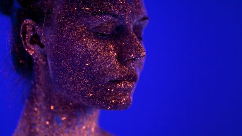 Une femme avec des paillettes sur le visage sur un fond bleu