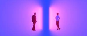 un homme et une femme traversent deux portes lumineuses violettes