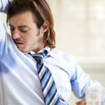Un homme en chemise et cravate se sent les aisselles humides