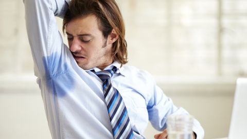 Un homme en chemise et cravate se sent les aisselles humides