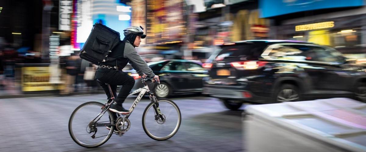 Amazon investit dans Deliveroo Un livreur en vélo, traverse un centre-ville