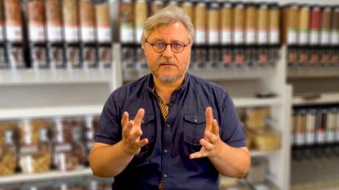 homme parlant de face devant des rayons de vrac