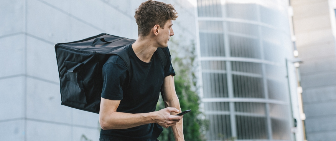 Comment les utilisateurs d'applications peuvent-ils changer les conditions de travail des livreurs ? Un homme à vélo avec un sac à dos pour livrer des produits alimentaires