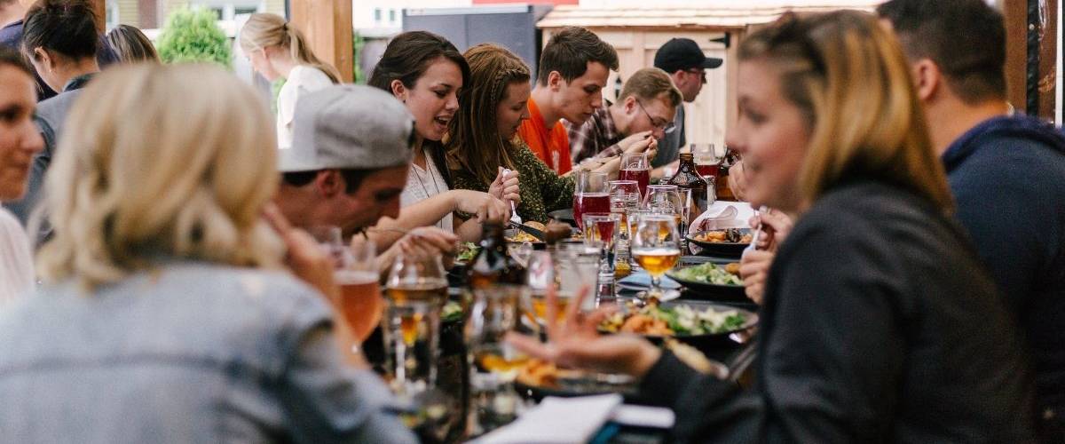 Et si vous demandiez à google de commander à votre place ? Un groupe d'amis dinent autour d'une table de restaurant fleurie et animée