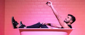 Un homme dans une baignoire rose, en train de prendre un selfie