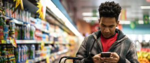 Homme au supermarché consulte son smartphone