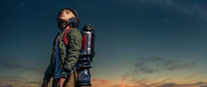 un enfant avec une fusée dans le dos regarde les étoiles