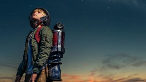 un enfant avec une fusée dans le dos regarde les étoiles