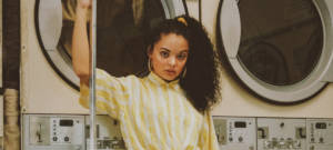 Une femme avec une chemise jaune dans une laverie vintage