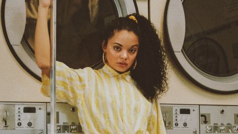 Une femme avec une chemise jaune dans une laverie vintage