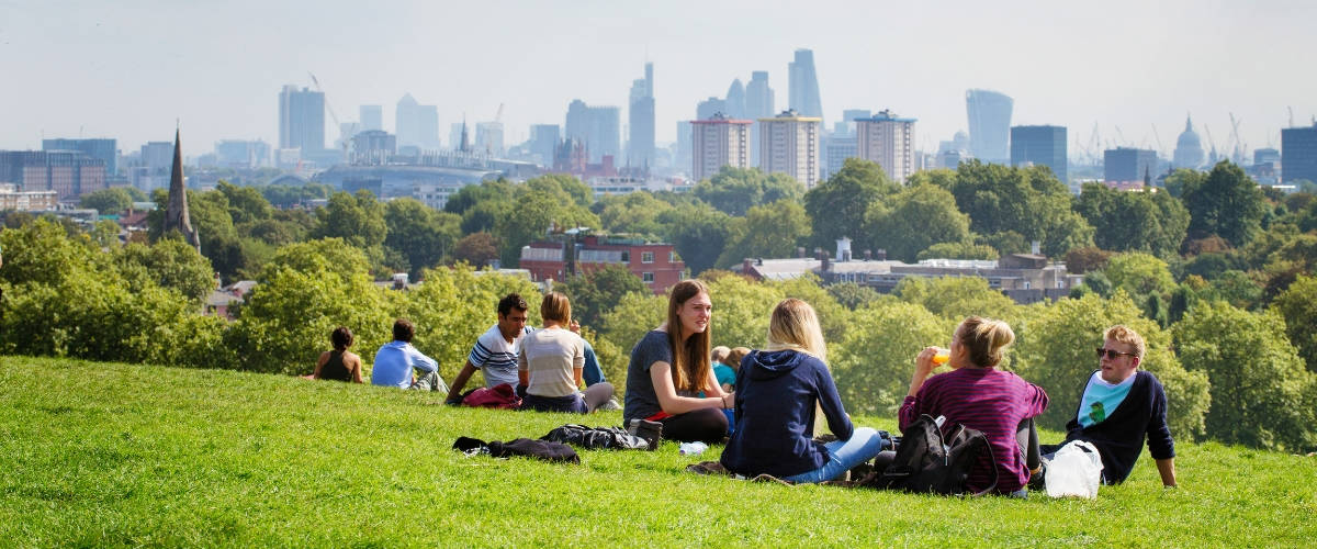Classement des villes les plus durables Des gens assis dans un parc avec la ville de Londres à l'horizon
