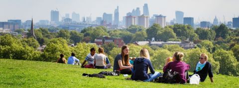 Classement des villes les plus durables Des gens assis dans un parc avec la ville de Londres à l'horizon