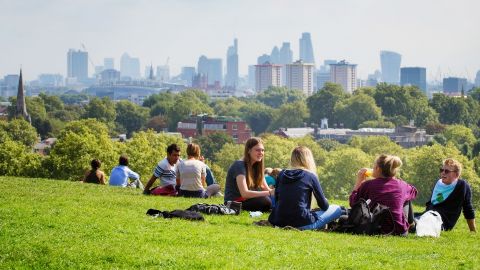 Des gens assis dans un parc avec la ville de Londres à l'horizon