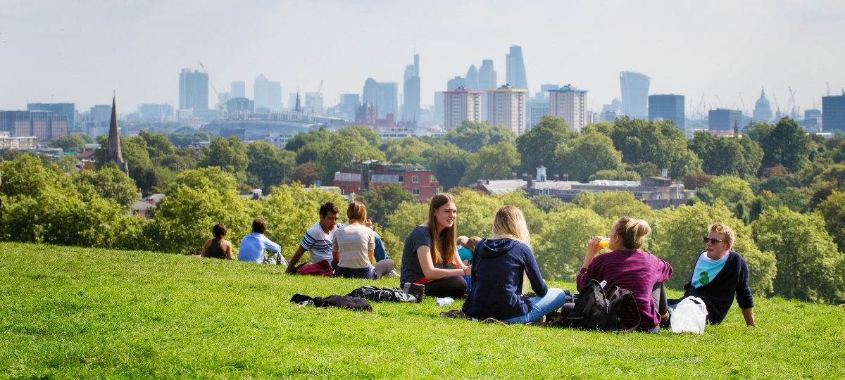 Classement des villes les plus durables Des gens assis dans un parc avec la ville de Londres à l'horizon