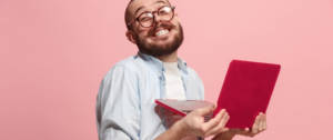 Un homme à lunettes est heureux avec son ordinateur portable