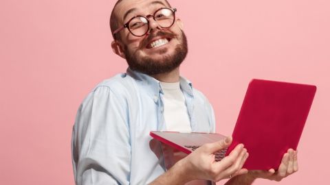 Un homme à lunettes est heureux avec son ordinateur portable